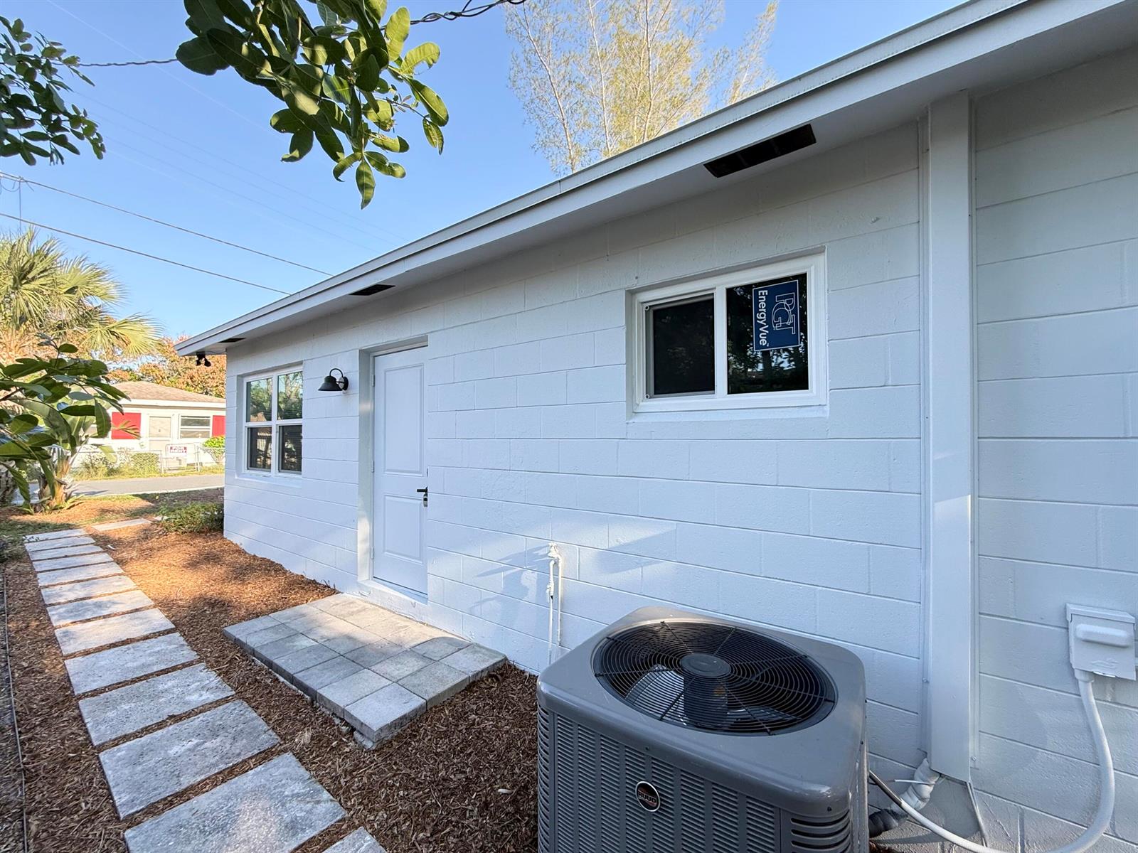 The exterior of a white concrete block house features a door, windows, and an AC unit — 912 SE Tarpon Avenue, Stuart FL 34994, STUART, FL