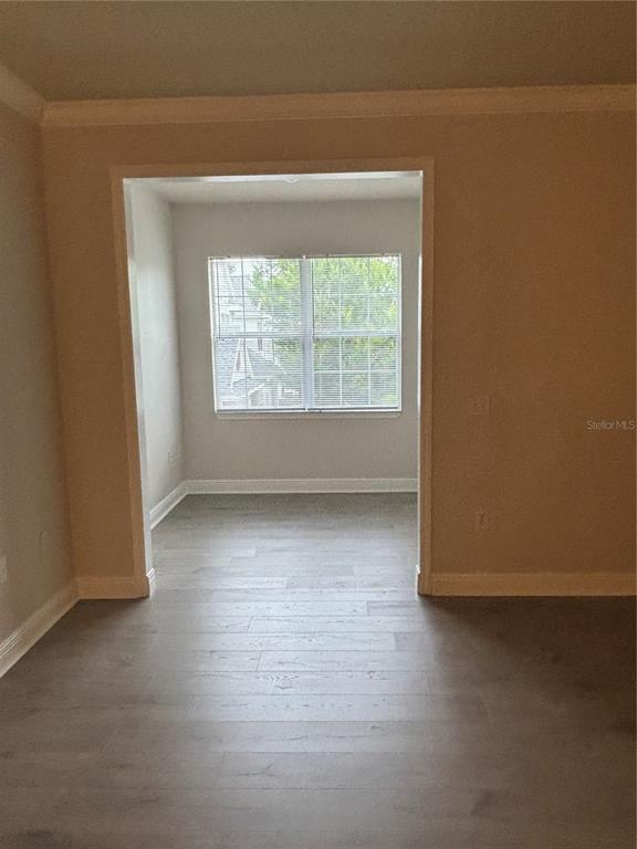 A room with light-colored wood-look flooring leads into a smaller alcove featuring a window — 417 SOUTHERN PECAN CIRCLE UNIT 207, WINTER GARDEN, FL