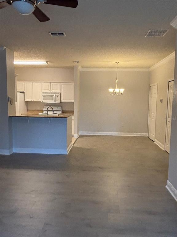 A kitchen with white cabinets and a dining area featuring a chandelier and wood flooring — 417 SOUTHERN PECAN CIRCLE UNIT 207, WINTER GARDEN, FL
