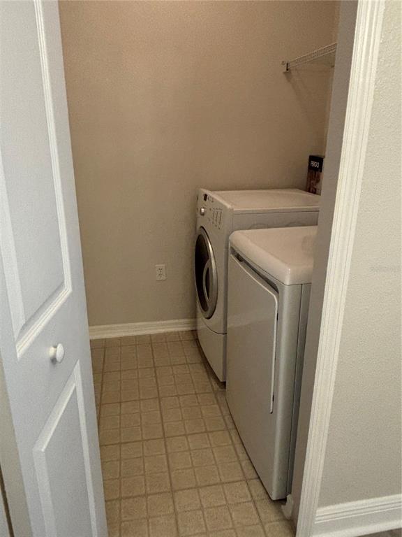 A laundry closet with tile flooring, a washer, a dryer, and a wire shelf — 417 SOUTHERN PECAN CIRCLE UNIT 207, WINTER GARDEN, FL