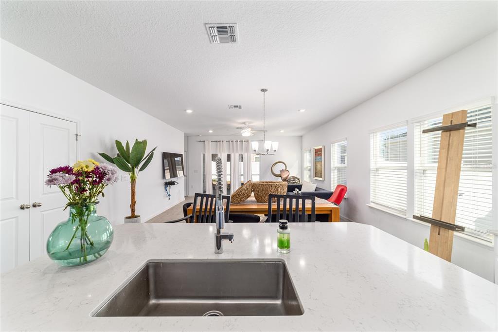 A kitchen island with a stainless steel sink overlooks an open-concept dining and living area — 7451 SW 76TH TERRACE, OCALA, FL