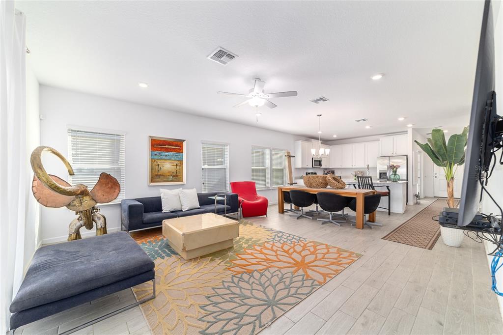 An open-concept living and dining area features light wood-look tile floors and white cabinetry — 7451 SW 76TH TERRACE, OCALA, FL