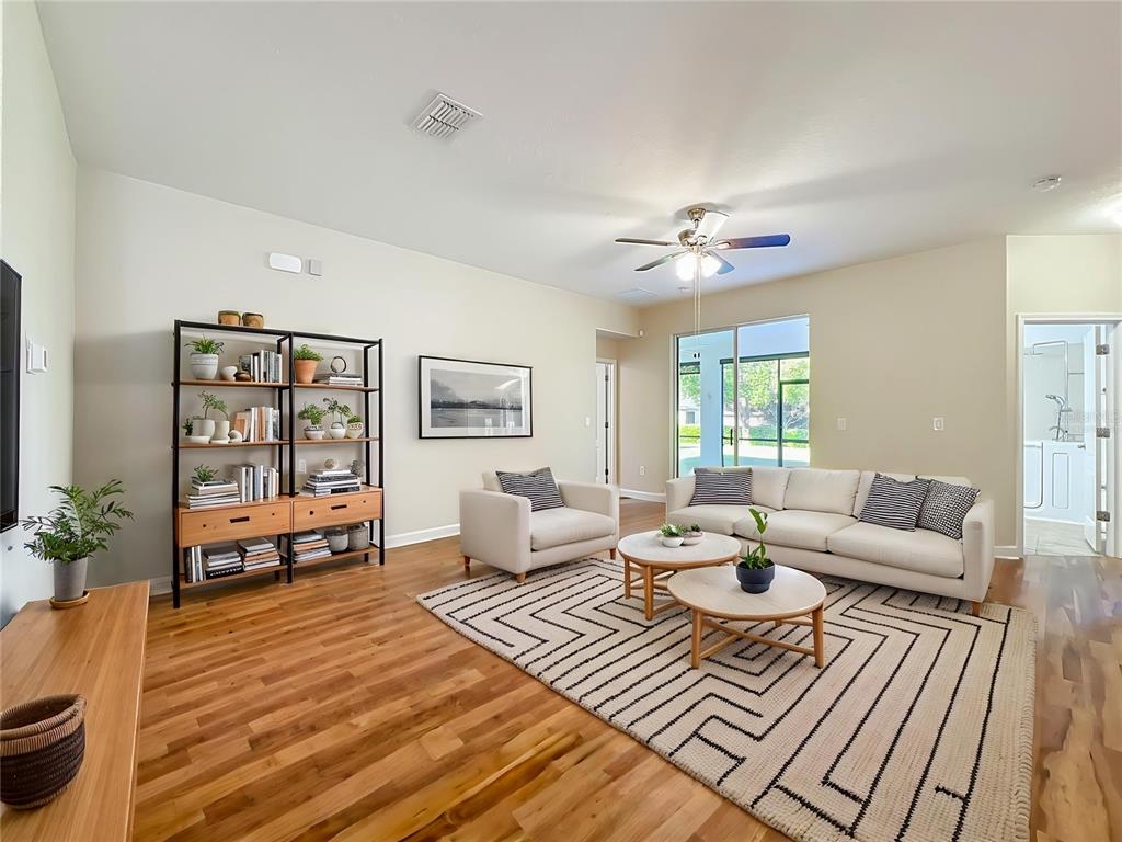 A living room features a white sofa, an armchair, a geometric rug, and a bookshelf — 4052 SERENA LANE, CLERMONT, FL
