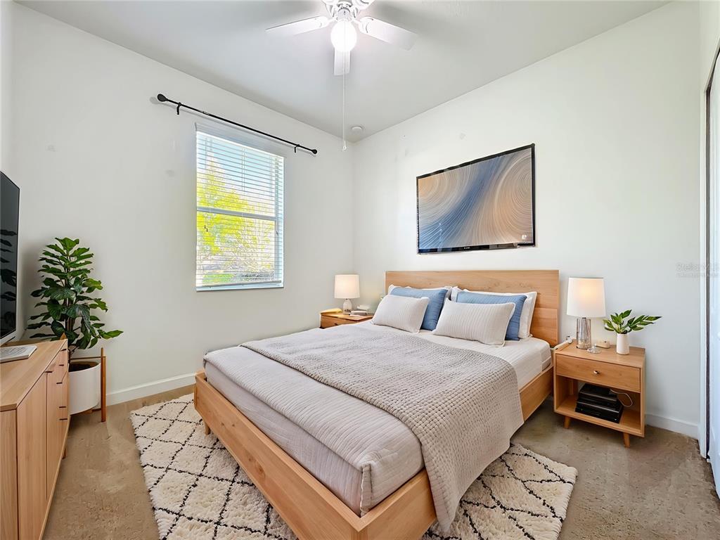 A bedroom features a wooden bed frame, light-colored walls, a window with blinds, and a rug — 4052 SERENA LANE, CLERMONT, FL