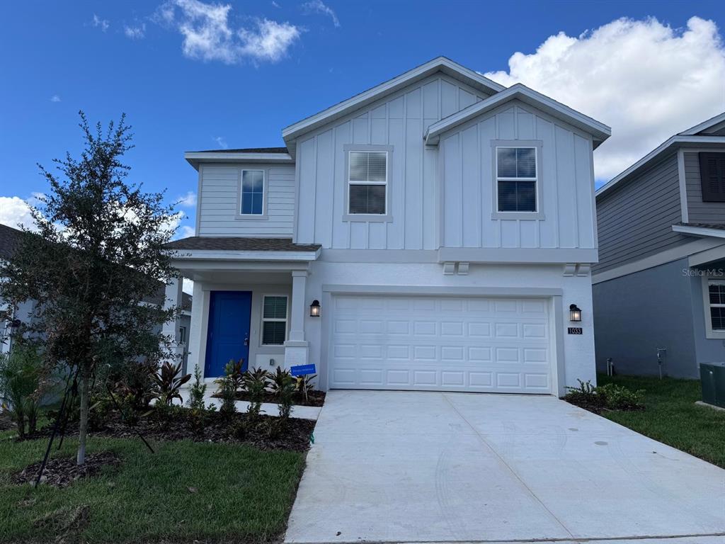A two-story house with white vertical siding, a blue front door, and a two-car garage — 1033 WATERFALL BOULEVARD, DAVENPORT, FL