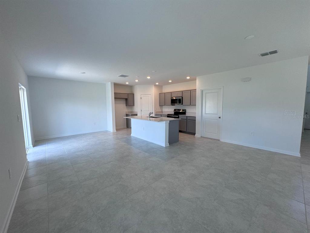 An open-concept kitchen with a central island, grey cabinetry, and light tile flooring — 1033 WATERFALL BOULEVARD, DAVENPORT, FL