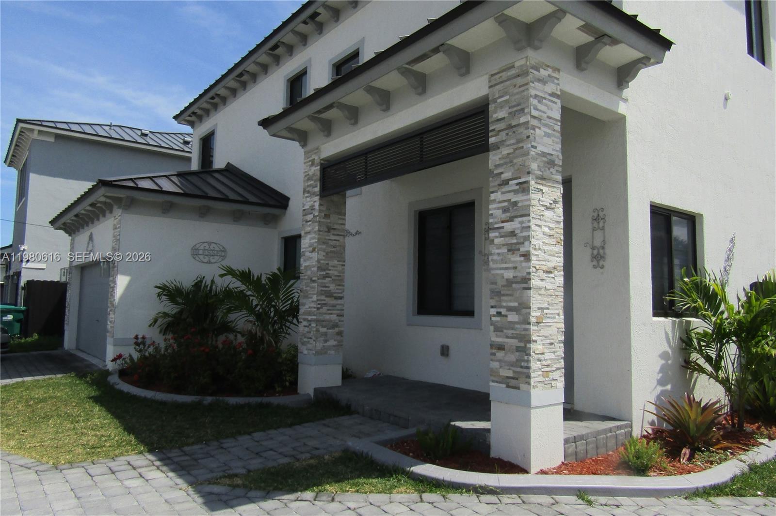 The exterior of a two-story house features a stone-clad entryway, a garage, and landscaping — 11998 SW 232nd St, Miami FL 33170, MIAMI, FL