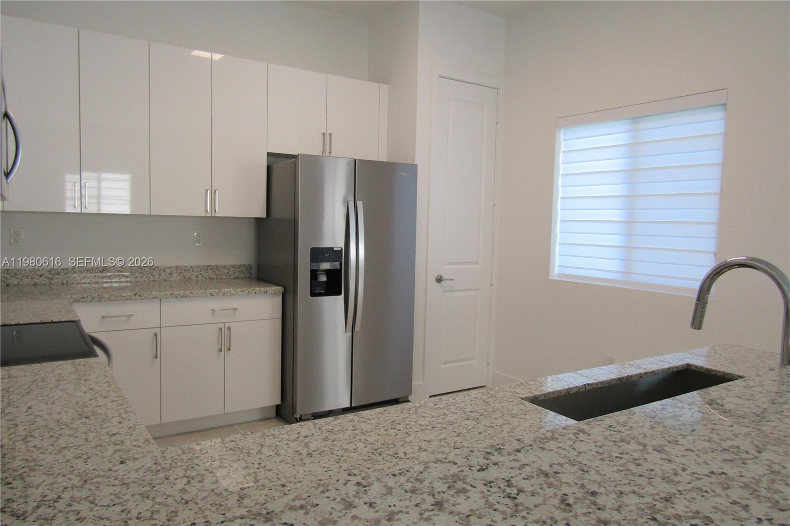 A kitchen features white cabinets, granite countertops, stainless steel appliances, and a window — 11998 SW 232nd St, Miami FL 33170, MIAMI, FL