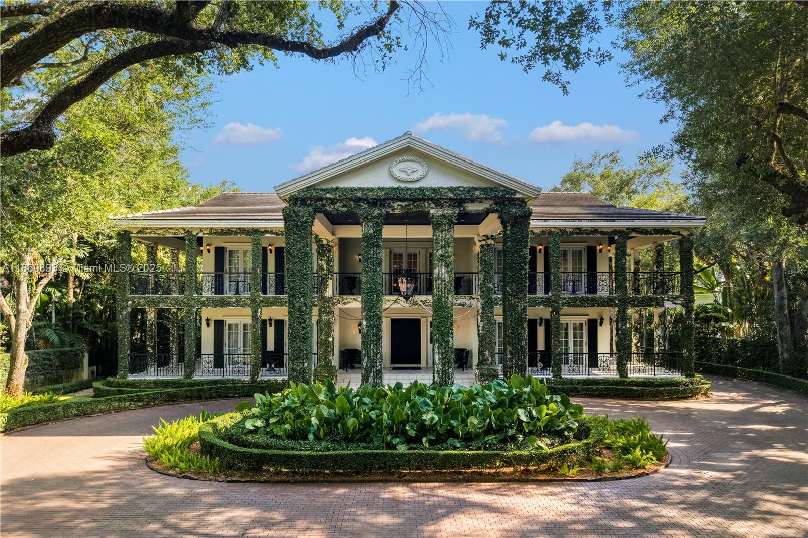 A two-story Southern colonial-style mansion features a columned porch covered in climbing ivy — 612 Sunset Dr, Coral Gables FL 33143, CORAL GABLES, FL