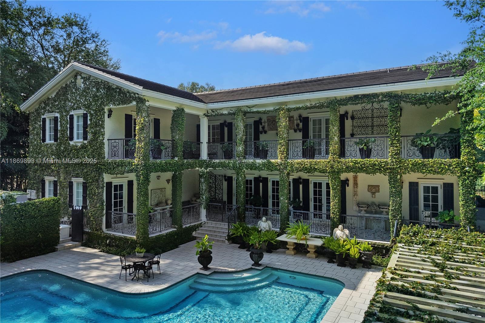 A two-story house with ivy-covered walls, balconies, and a swimming pool in the backyard — 612 Sunset Dr, Coral Gables FL 33143, CORAL GABLES, FL