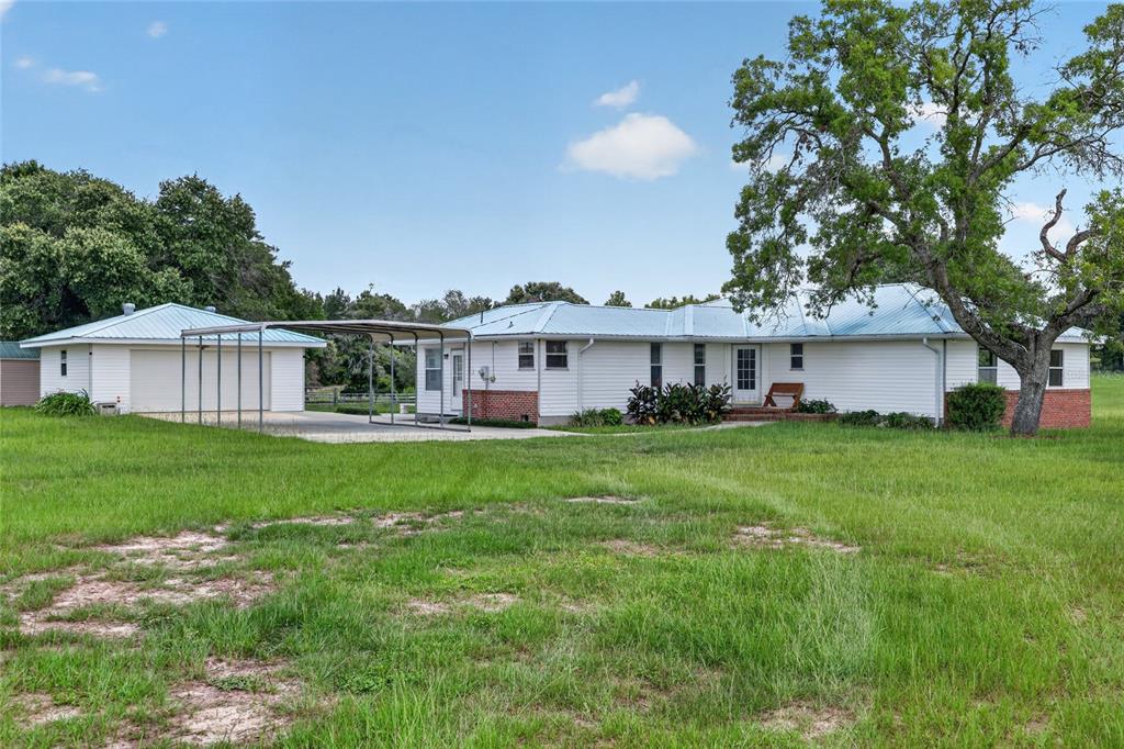 A white single-story house with a metal roof, brick accents, and an attached metal carport — 20500 NW 27TH STREET, MORRISTON, FL
