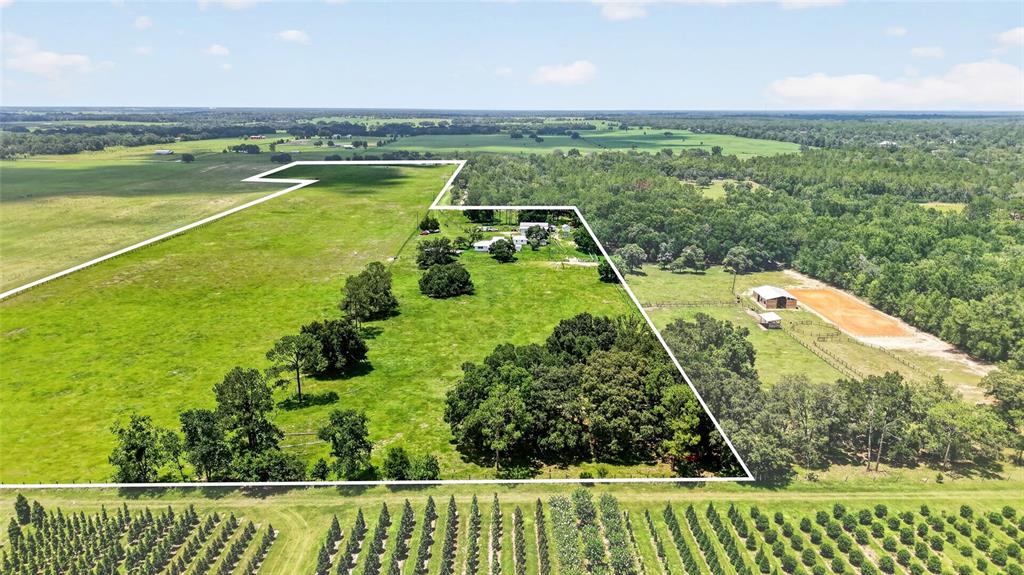 An aerial view shows a rural property with a house, outbuildings, and fenced pastures — 20500 NW 27TH STREET, MORRISTON, FL