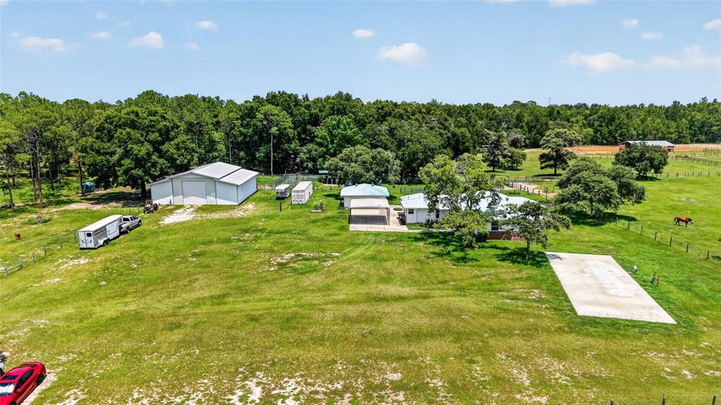 An aerial view shows a rural property with a house, a large workshop, and pasture — 20500 NW 27TH STREET, MORRISTON, FL