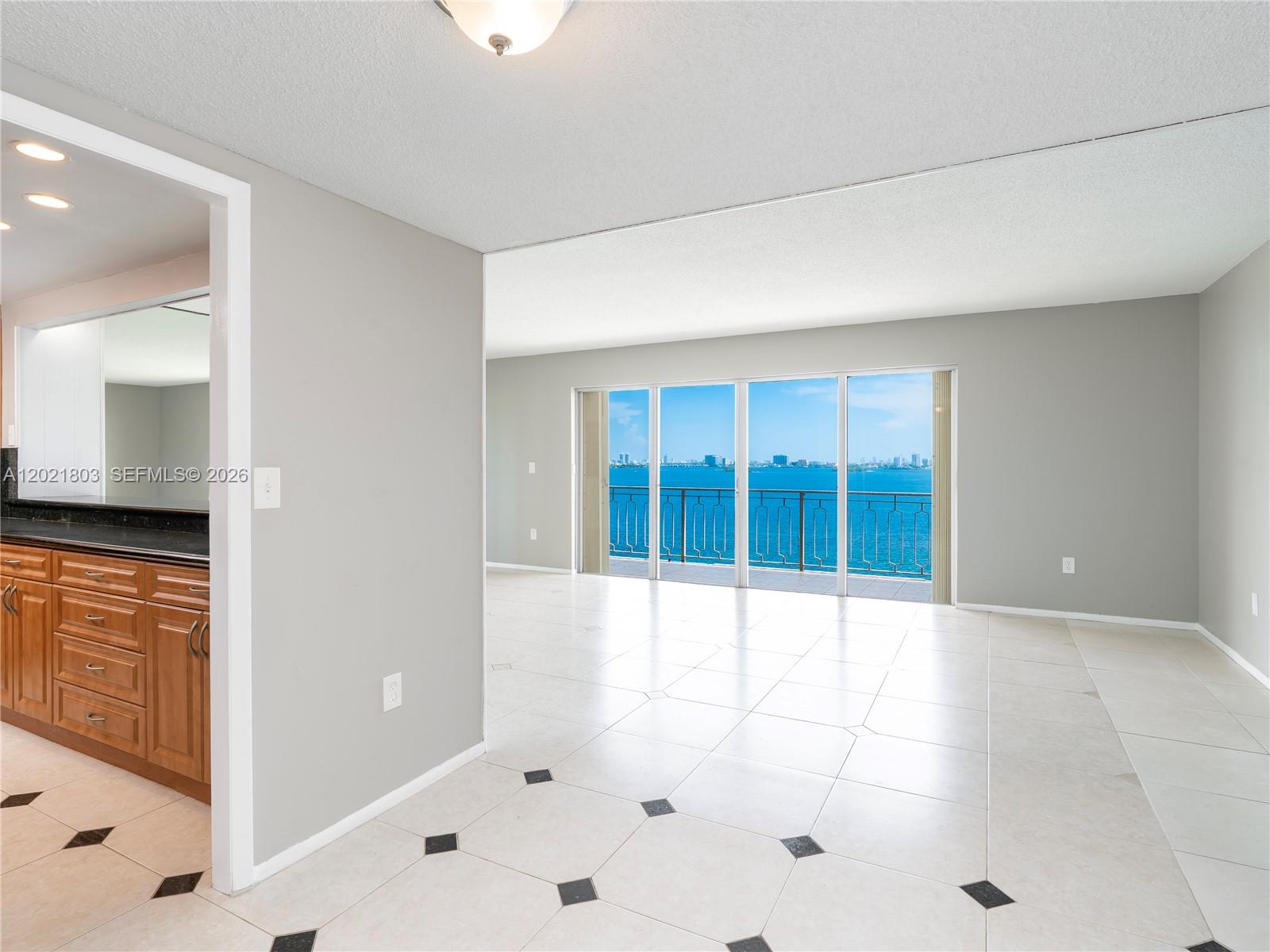 An interior view shows a tiled living area opening to a balcony with water views — 11111 Biscayne Blvd # 912, Miami FL 33181, MIAMI, FL