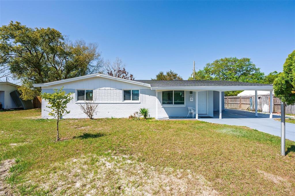 A single-story white brick house features a front porch, a carport, and a grassy yard — 410 SANTIAGO AVENUE, ORLANDO, FL