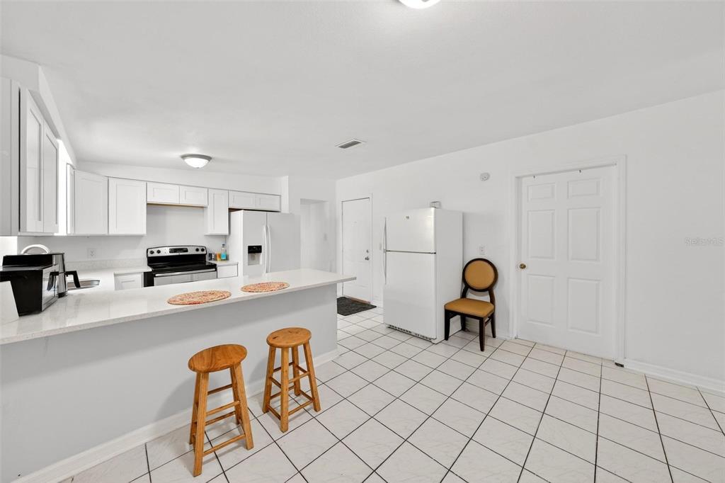 A kitchen with white cabinets, a breakfast bar, and white tile flooring — 410 SANTIAGO AVENUE, ORLANDO, FL