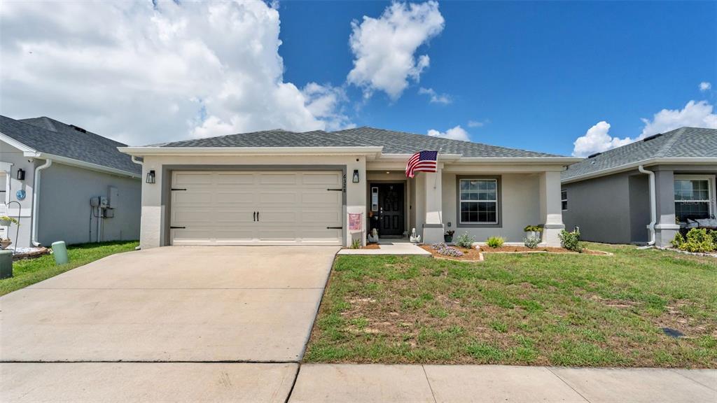 A single-story suburban house with a two-car garage, gray roof, and a front lawn — 6328 GARDNER DRIVE, LAKELAND, FL