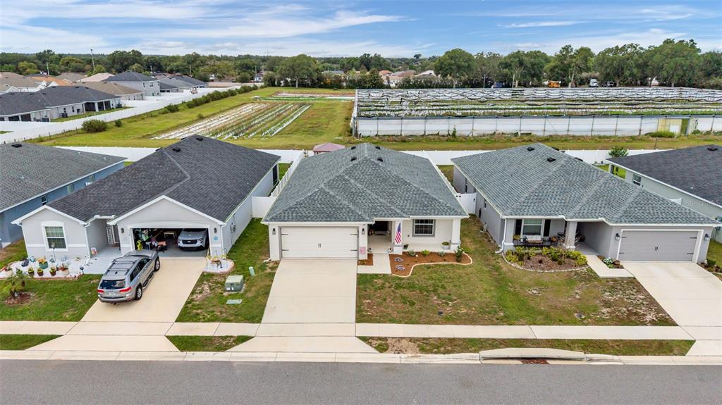 An aerial view shows three suburban houses with garages and driveways facing a paved street — 6328 GARDNER DRIVE, LAKELAND, FL