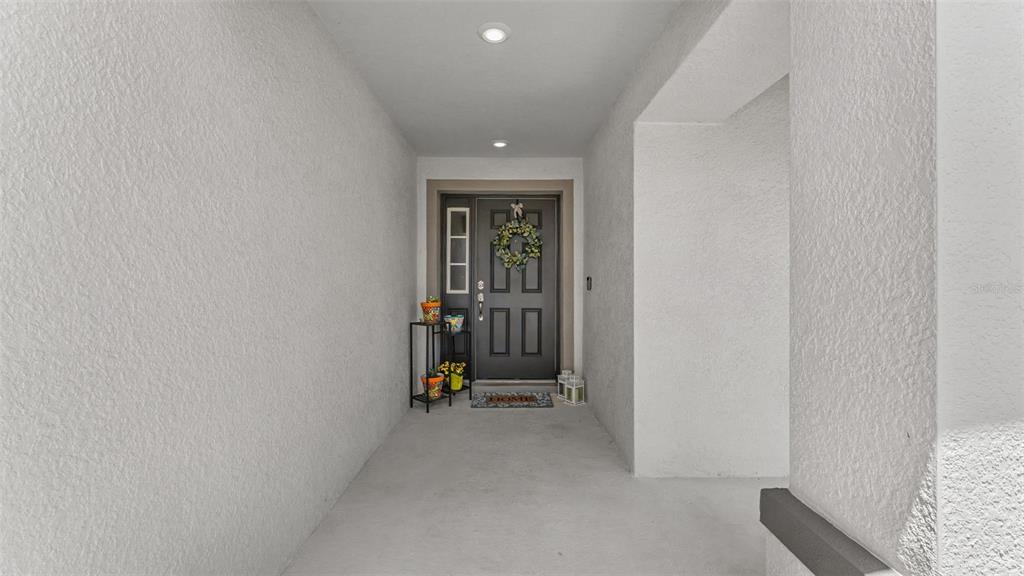 A covered entryway features a dark gray front door with glass panels and a wreath — 6328 GARDNER DRIVE, LAKELAND, FL