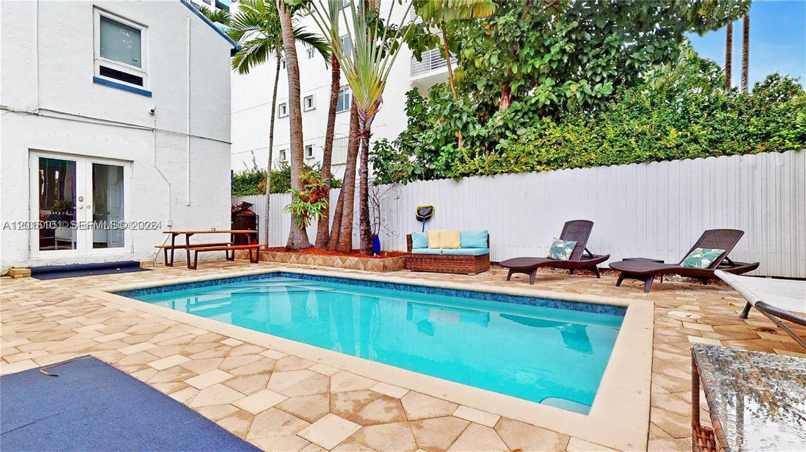 A rectangular swimming pool is surrounded by a stone patio, lounge chairs, and palm trees — 1400 West Ave, Miami Beach FL 33139, MIAMI BEACH, FL