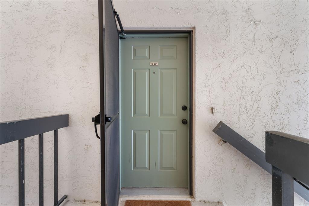 A light green door with unit number C-201 is set in a white stucco wall — 19505 QUESADA AVENUE UNIT C201, PORT CHARLOTTE, FL