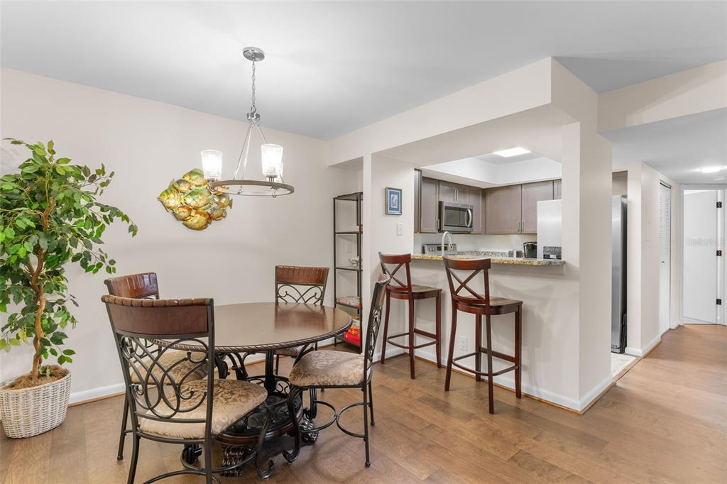 A dining area with a round table and chairs adjacent to a kitchen with bar seating — 19505 QUESADA AVENUE UNIT C201, PORT CHARLOTTE, FL