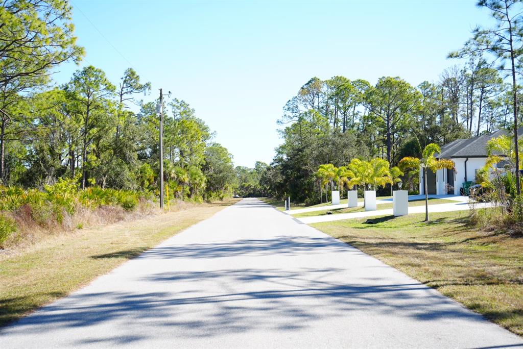 A paved road stretches between a wooded area and a house with palm trees — 13101 RANKIN AVENUE, PORT CHARLOTTE, FL