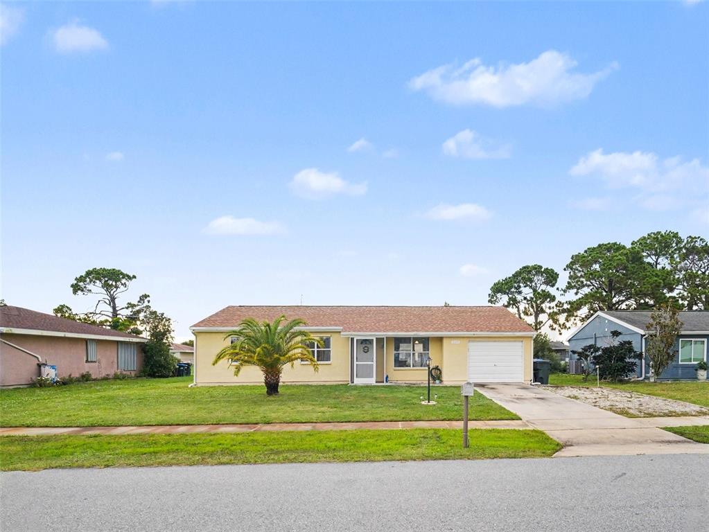 A single-story yellow house with a palm tree, a front porch, and a one-car garage — 2473 FAIRBROOK STREET, NORTH PORT, FL