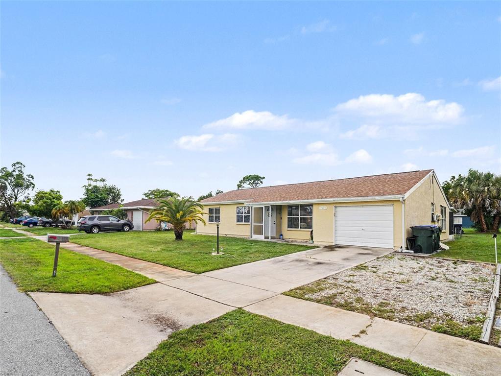 A single-story yellow house with a white garage door and a front lawn — 2473 FAIRBROOK STREET, NORTH PORT, FL