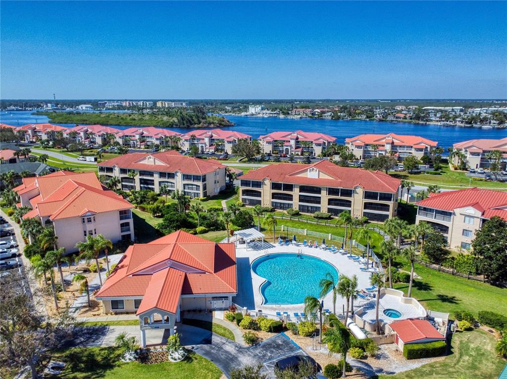 An aerial view of a multi-story apartment complex with a swimming pool and clubhouse — 451 BOUCHELLE DRIVE UNIT 104, NEW SMYRNA BEACH, FL