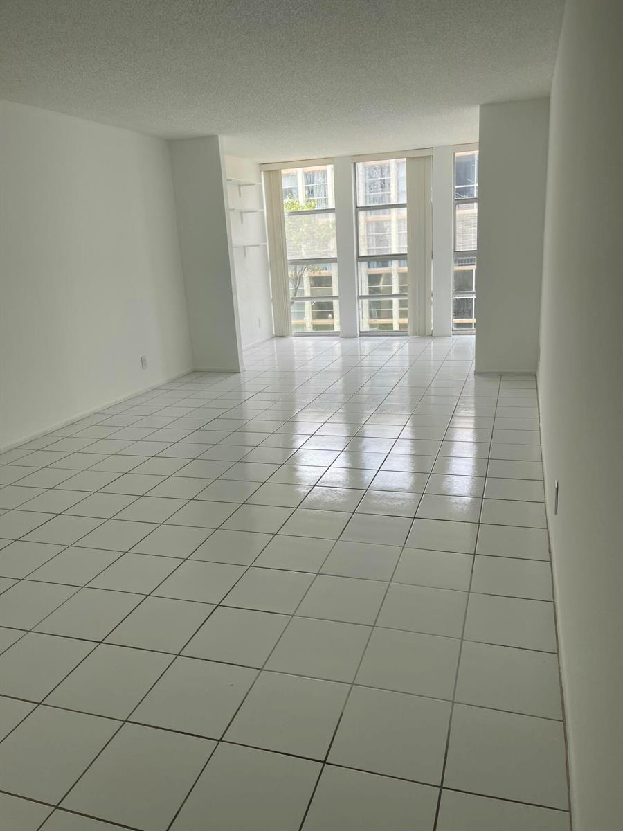 An empty room with white tile flooring, white walls, and floor-to-ceiling windows — 801 Three Island Boulevard # 306, FL 33009, FL