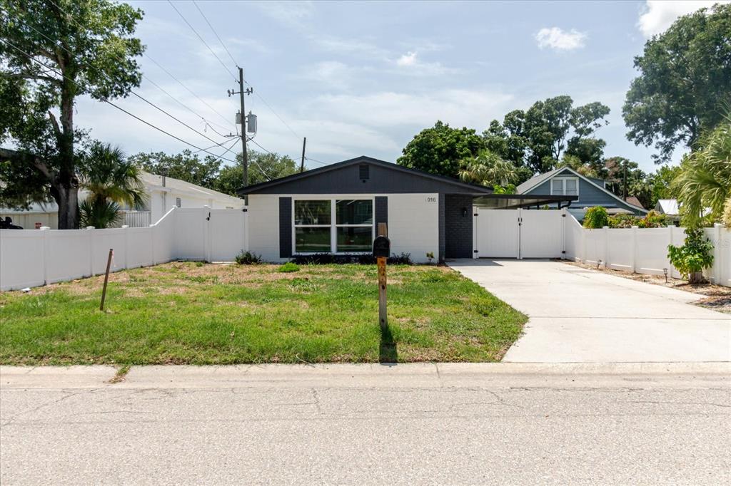 A single-story house with a white brick exterior, dark trim, and a fenced front yard — 916 17TH STREET N, ST PETERSBURG, FL