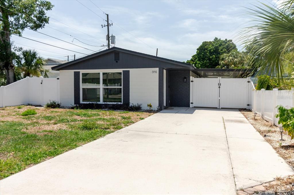 A single-story house with a white and dark gray exterior, a concrete driveway, and white fencing — 916 17TH STREET N, ST PETERSBURG, FL