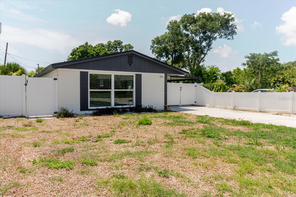 A single-story house with white walls, dark trim, and a white fence in the yard — 916 17TH STREET N, ST PETERSBURG, FL