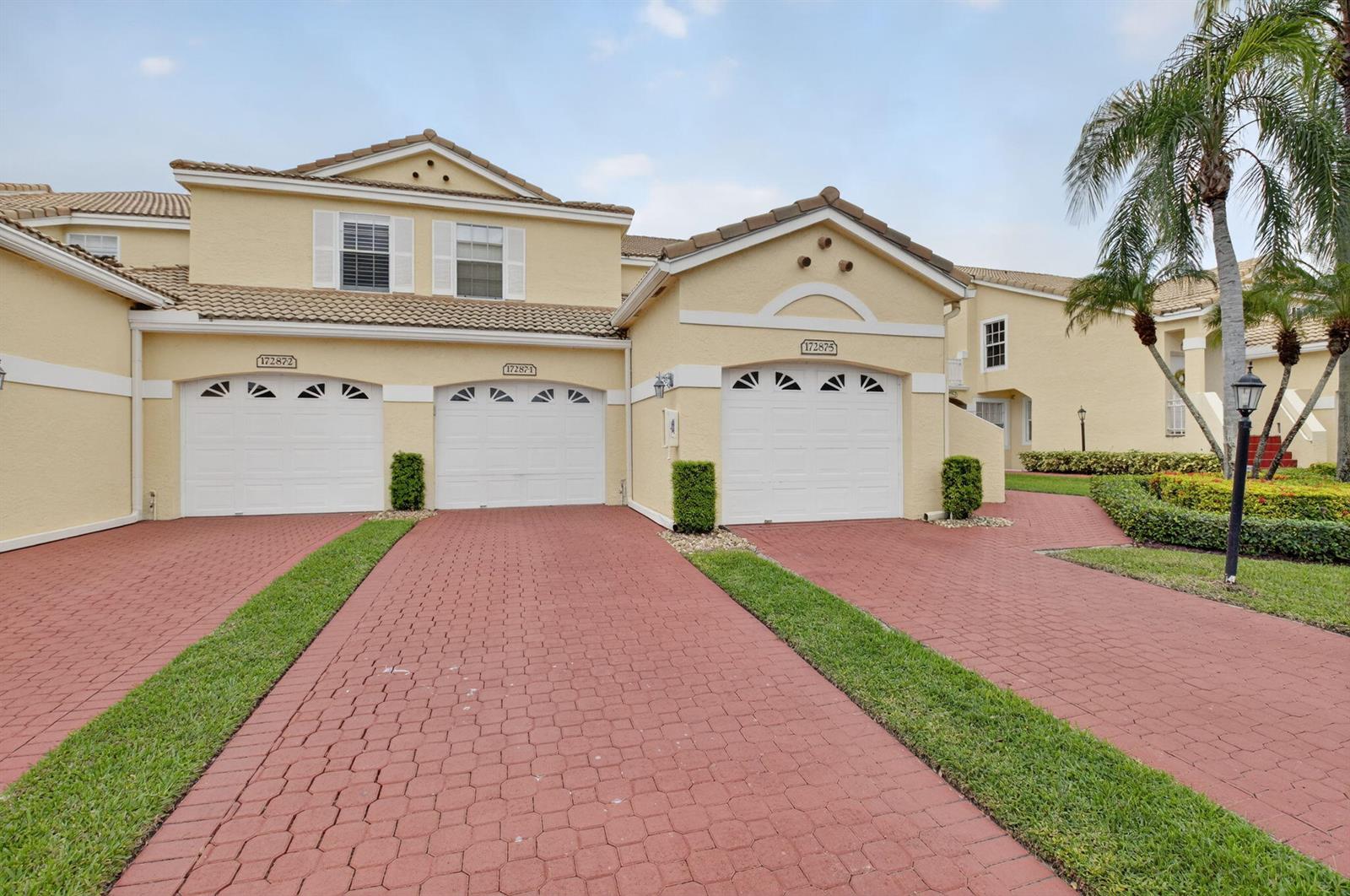 A multi-unit residential building features three garage doors, red brick driveways, and palm trees — 17287 Boca Club Boulevard # 1, Boca Raton FL 33487, BOCA RATON, FL