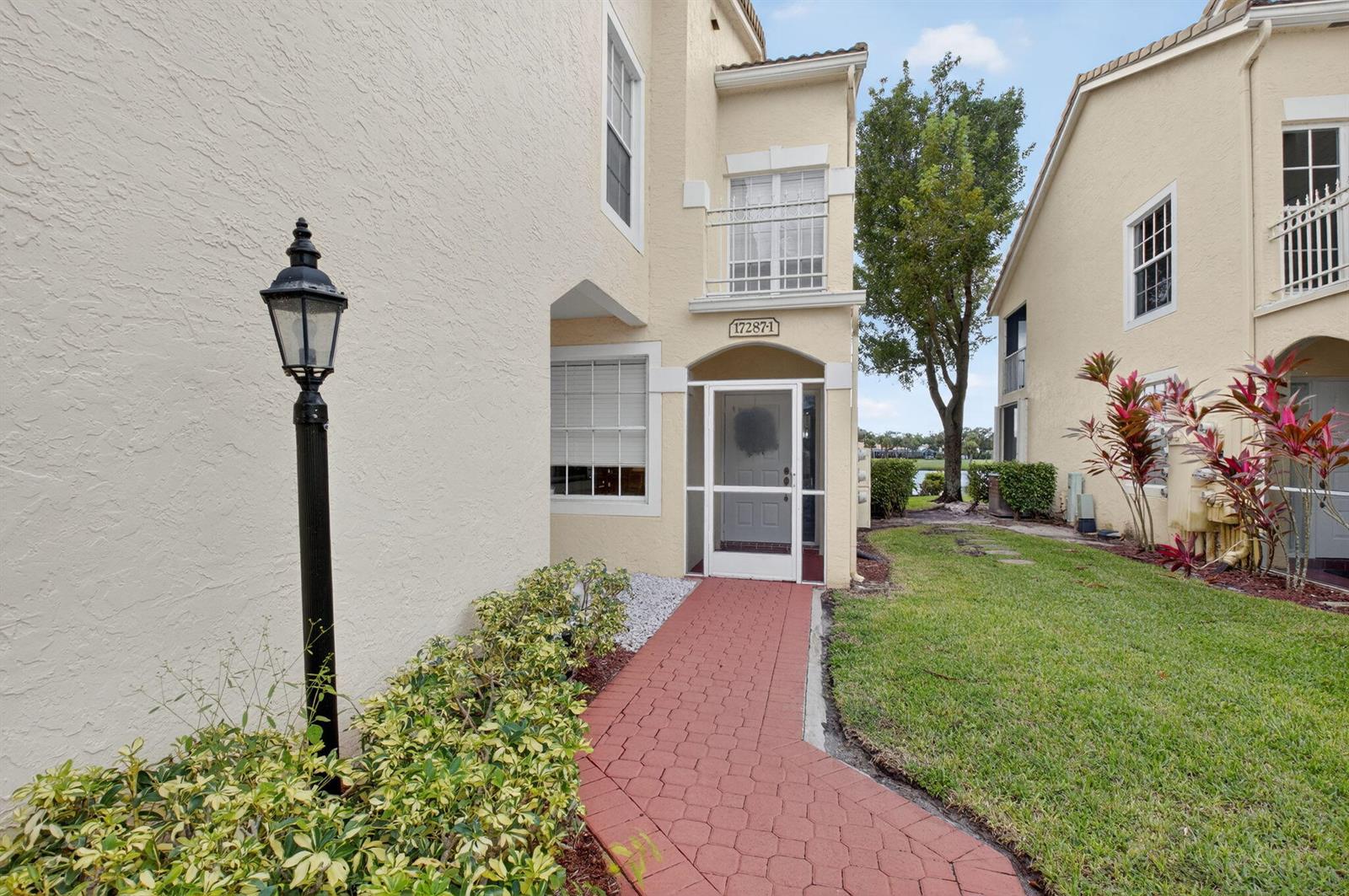A red brick walkway leads to the front entrance of a two-story beige stucco building — 17287 Boca Club Boulevard # 1, Boca Raton FL 33487, BOCA RATON, FL