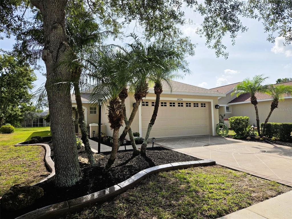 A tan house with a two-car garage and palm trees in the front yard — 14224 GNATCATCHER TERRACE, BRADENTON, FL