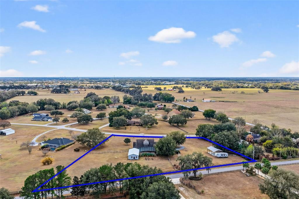 An aerial view shows a residential property with a house, outbuildings, and trees outlined in blue — 4564 COUNTY ROAD 103G, OXFORD, FL