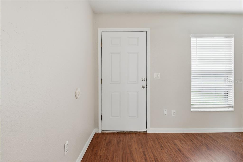A room with light-colored walls, wood-look flooring, a white entry door, and a window — 9271 N PEACHTREE WAY, CITRUS SPRINGS, FL