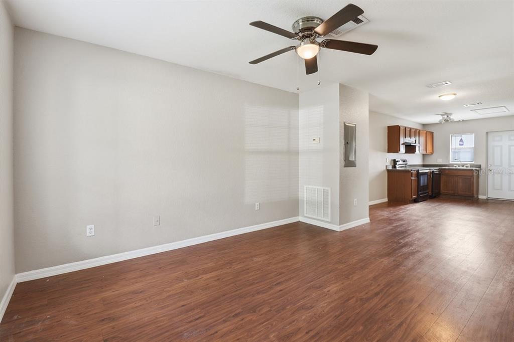 An open-concept living area with wood-look flooring, a ceiling fan, and an adjacent kitchen — 9271 N PEACHTREE WAY, CITRUS SPRINGS, FL