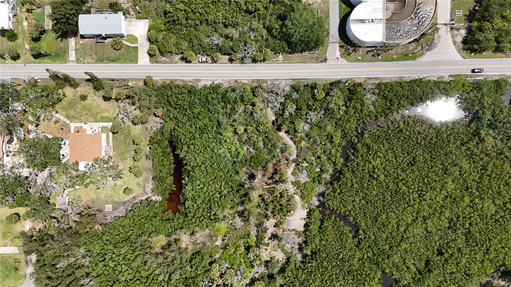 An aerial view shows a wooded lot with a small pond next to a road — MAIN STREET, NEW PORT RICHEY, FL