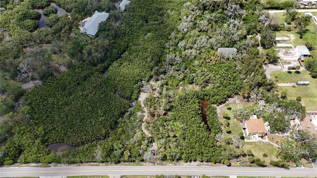 An aerial view shows a wooded lot with a small creek next to residential houses — MAIN STREET, NEW PORT RICHEY, FL