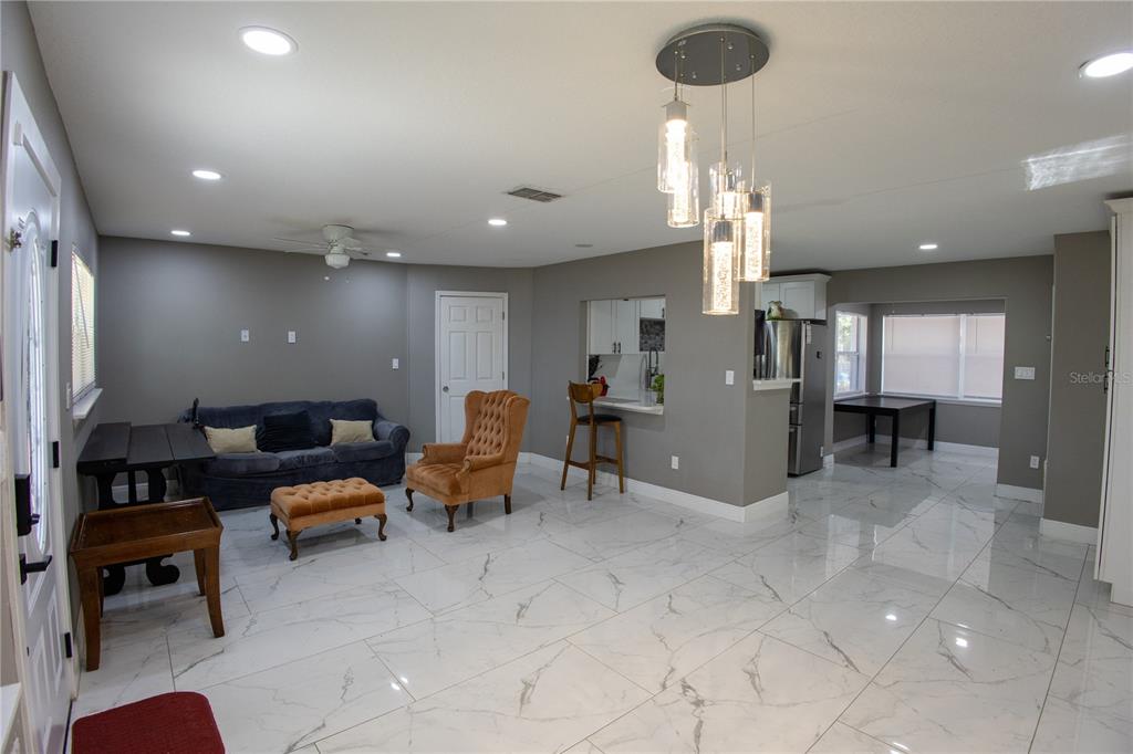 A living room with white marble-look tile floors, a blue sofa, and a pendant light fixture — 1741 S HAWTHORNE AVENUE, APOPKA, FL