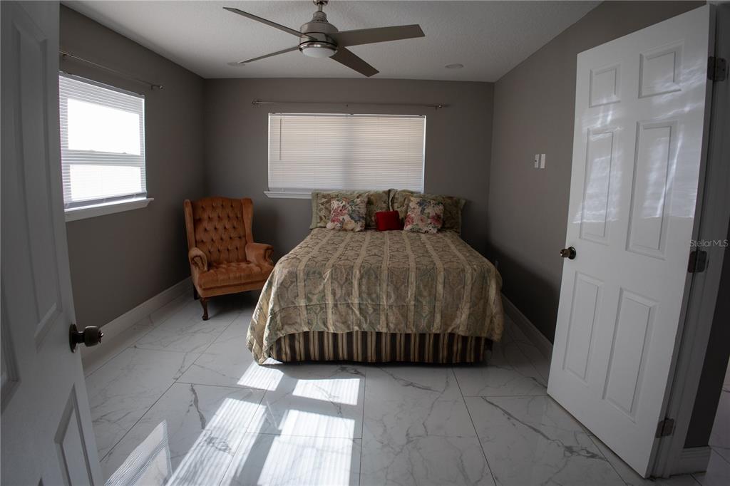 A bedroom features gray walls, white marble-look tile flooring, a bed, and an orange chair — 1741 S HAWTHORNE AVENUE, APOPKA, FL