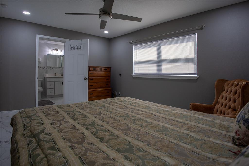 A bedroom features gray walls, a patterned bedspread, a wooden dresser, and an attached bathroom — 1741 S HAWTHORNE AVENUE, APOPKA, FL