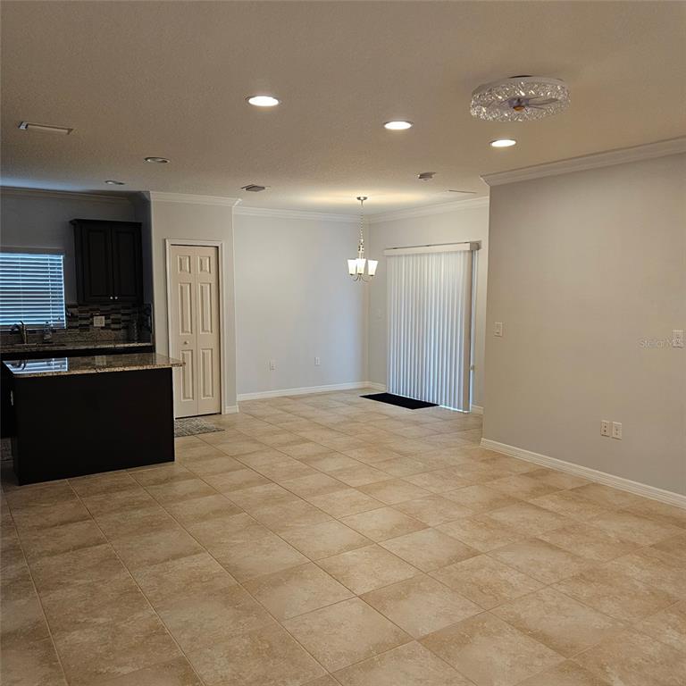 An open-concept kitchen and dining area features tile flooring, dark cabinetry, and recessed lighting — 11680 SW ROWENA STREET, PORT ST LUCIE, FL