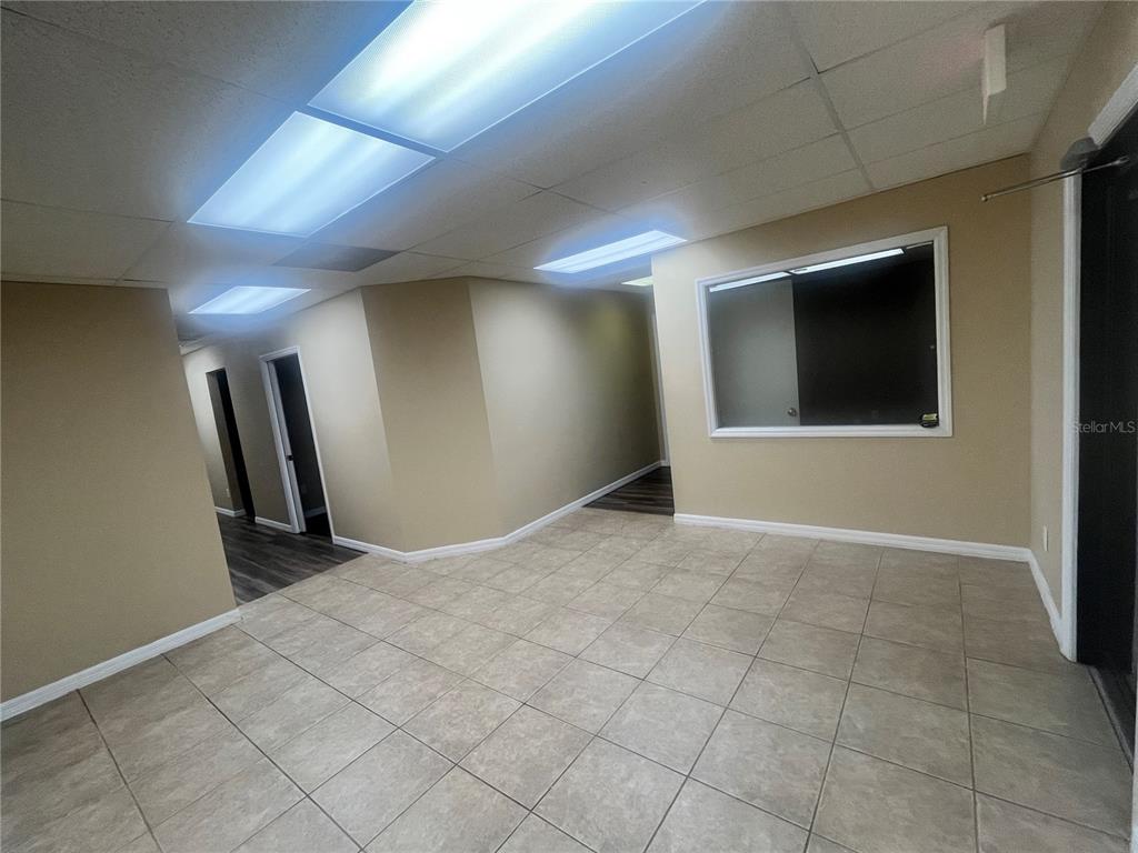 An interior office space features beige walls, tiled flooring, recessed lighting, and a window cutout — 141 E CENTRAL AVENUE UNIT 350, WINTER HAVEN, FL