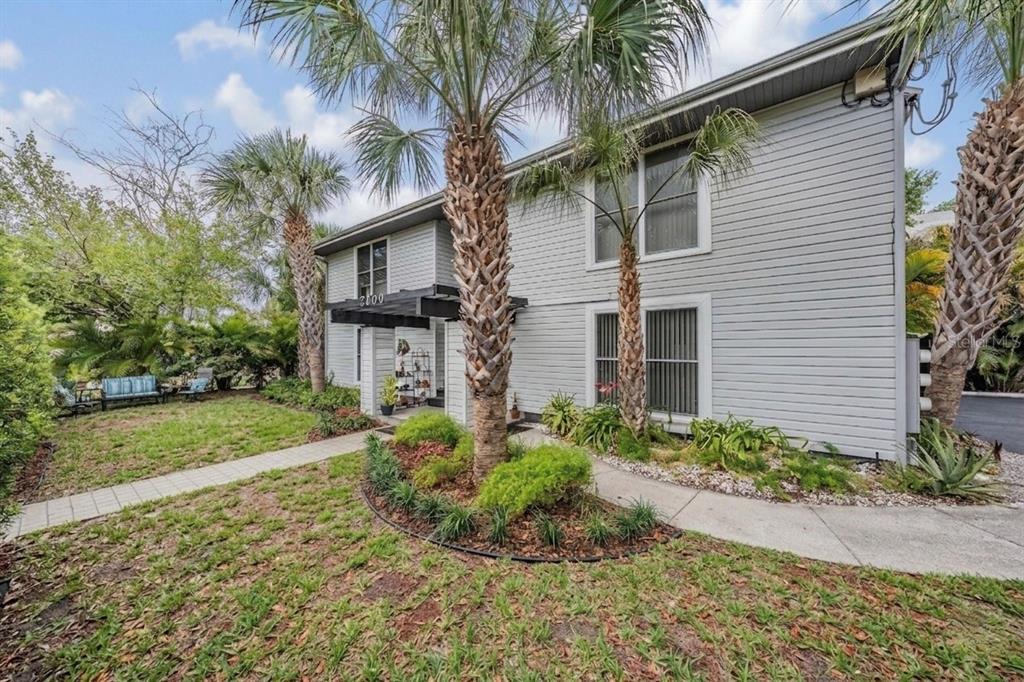A two-story house with gray siding, palm trees, and a walkway leading to the entrance — 2109 W DE LEON STREET, TAMPA, FL
