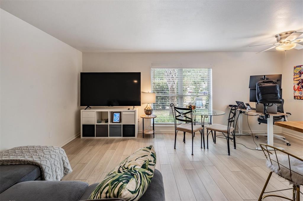 A living room features light wood flooring, a large television on a storage unit, and a desk — 2109 W DE LEON STREET, TAMPA, FL