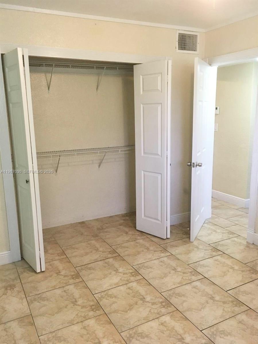 A room features beige tile flooring, a white closet with bifold doors, and an open doorway — 4250 SW 67th Ave # 32, Miami FL 33155, MIAMI, FL